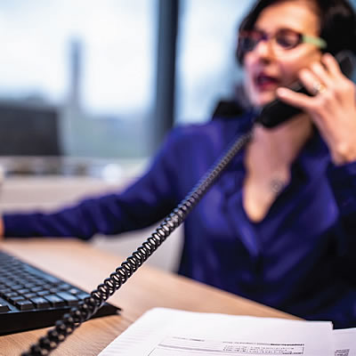 A lady at a desk with a telephone to her ear
