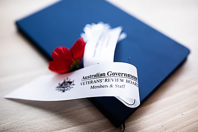 A blue document portfolio with a poppy on top and a label with the words Australian Government Veterans' Review Board Members and Staff.