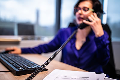 A lady at a desk with a telephone to her ear